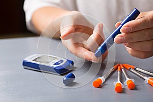 Woman checking blood glucose level using syringe pen with home glucometer.