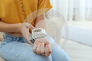 Woman checking blood pressure at home, closeup with space for text.