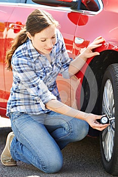 Woman Checking Car Tyre Pressure Using Gauge