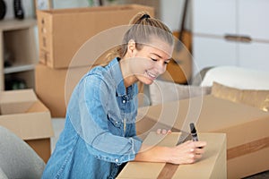 woman checking cardboard box before moving to new apartment