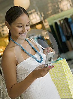 Woman Checking Cell Phone While Shopping in clothing store