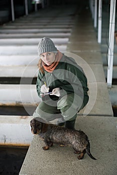 Woman checking fish reservoirs, writing in notebook