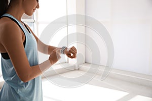 Woman checking fitness tracker in gym, closeup. Space for text