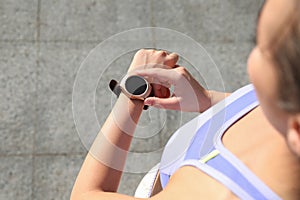 Woman checking fitness tracker after training outdoors, closeup