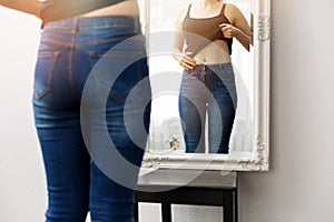 Woman checking her body in front of mirror