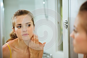 Woman checking her face in mirror in bathroom