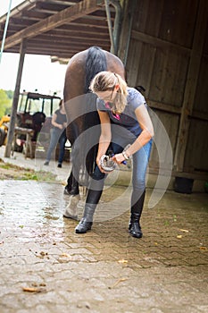 Woman Checking Her Horse`s Hooves