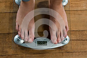 Woman checking her weight on a weighing machine