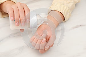 Woman checking infant formula temperature at white table, closeup. Baby milk