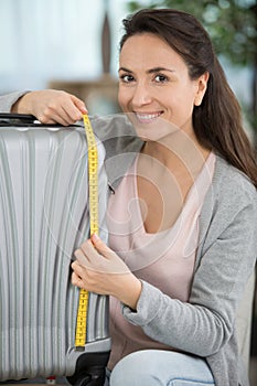 woman checking luggage measurments before vacation