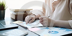 Woman checking paperwork from accounting department to analyse number on document, using laptop check business database,