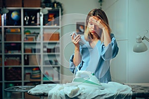 Woman checking phone burning a shirt while ironing photo