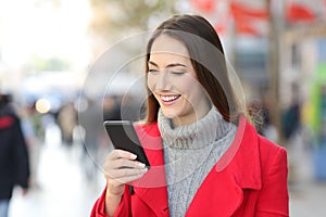 Woman checking phone messages on the street in winter