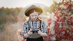 Woman checking pictures on analog digital photo camera on autumn background