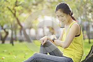 Woman checking progress on smart watch connect listen music to earphone, wearable fitness device. Sporty looking heart rate watch