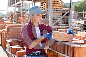 Woman checking quality of bricks at construction store