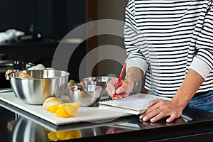 Woman checking recipe while cooking apple pie