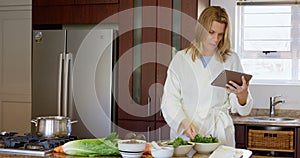 Woman checking recipe on digital tablet in kitchen 4k