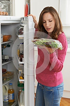 Woman Checking Sell By Date On Salad Bag In Refrigerator