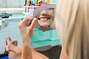 Woman checking teeth in mirror. Female at the dentist office.