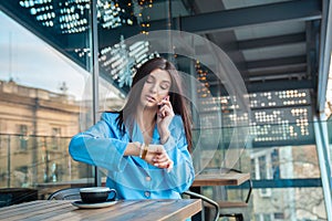 Woman checking time and caling a friend in a coffee shop