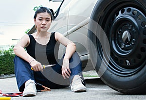 A woman is checking tyre of car