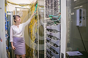 Woman checks the connection of the Internet optical wires in the server room of the data center. Girl is next to the powerful