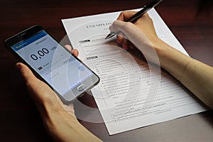 A woman checks her account balance on phone. Lack of money, filling out unemployment benefits form.  All screen graphics are made