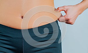 Woman checks and pinching excess fat on her hip