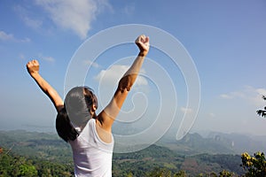 Woman cheering open arms at mountain peak