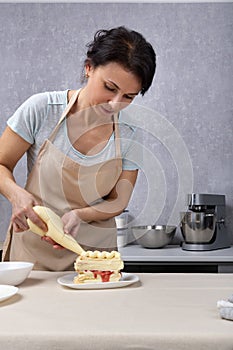 Woman chef decorates cake with culinary bag. Vertical frame