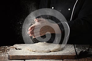 Woman chef hand clap with splash of white flour on a black background