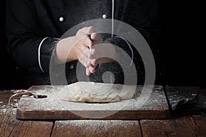 Woman chef hand clap with splash of white flour on a black background