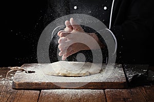 Woman chef hand clap with splash of white flour on a black background