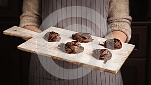 Woman chef holding wooden board with fettuccine nests