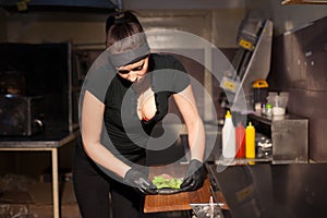 Woman chef in the kitchen preparing a hamburger sandwich