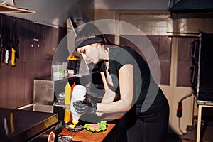 Woman chef in the kitchen preparing a hamburger sandwich