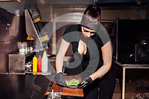 Woman chef in the kitchen preparing a hamburger sandwich