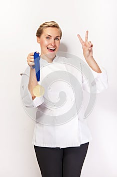 Woman in chef outfit and first prize medal smiling. Showing two