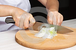 Woman chef prepares onions in the kitchen.