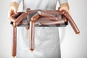 A woman chef is showing a heap of homemade Turkish sucuk or sausage on a tray