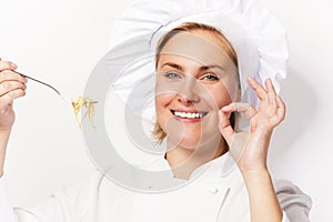 Woman chef showing a sign perfect, with pasta noodle on fork, ov