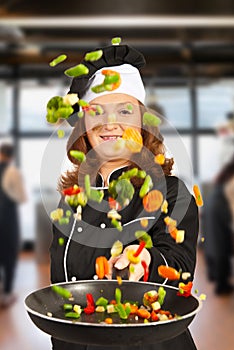 Woman chef tossing vegetables