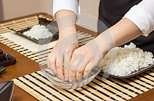 Woman chef wetting fingers to close sushi rolls