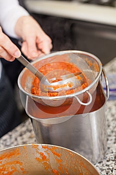 Woman chef whisking boiled tomato sauce