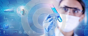 Woman chemist examining a test-tube with blue liquid while working at drugs synthesis in scientific background