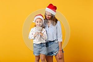 Woman child baby girl 4-5 years old in Christmas Santa hat. Mommy little kid daughter isolated on yellow background