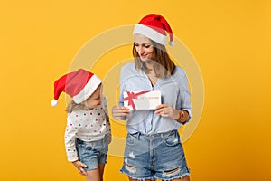 Woman child baby girl in Christmas Santa hat hold certificate. Mommy little daughter isolated on yellow background