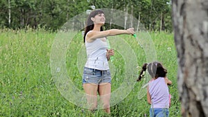Woman with a child blowing bubbles in field. woman with a child inflate bubbles. Family values