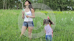 Woman with a child blowing bubbles in field. woman with a child inflate bubbles. Family values